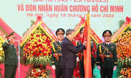 Tổng Bí thư Tô Lâm gắn Huân chương Hồ Chí Minh lên lá cờ truyền thống lực lượng Tình báo Quốc phòng Việt Nam. Ảnh: Bộ Quốc phòng