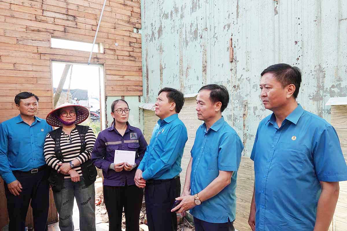Ong Nguyen Xuan Hung - Pho Chu tich Tong LDLDVN (thu 3 tu phai sang) trao ho tro cho doan vien Nguyen Thi Hai Yen tru phuong Hoanh Son, tinh Ha Tinh co nha bi toc mai do bao so 10. Anh: Tran Tuan.