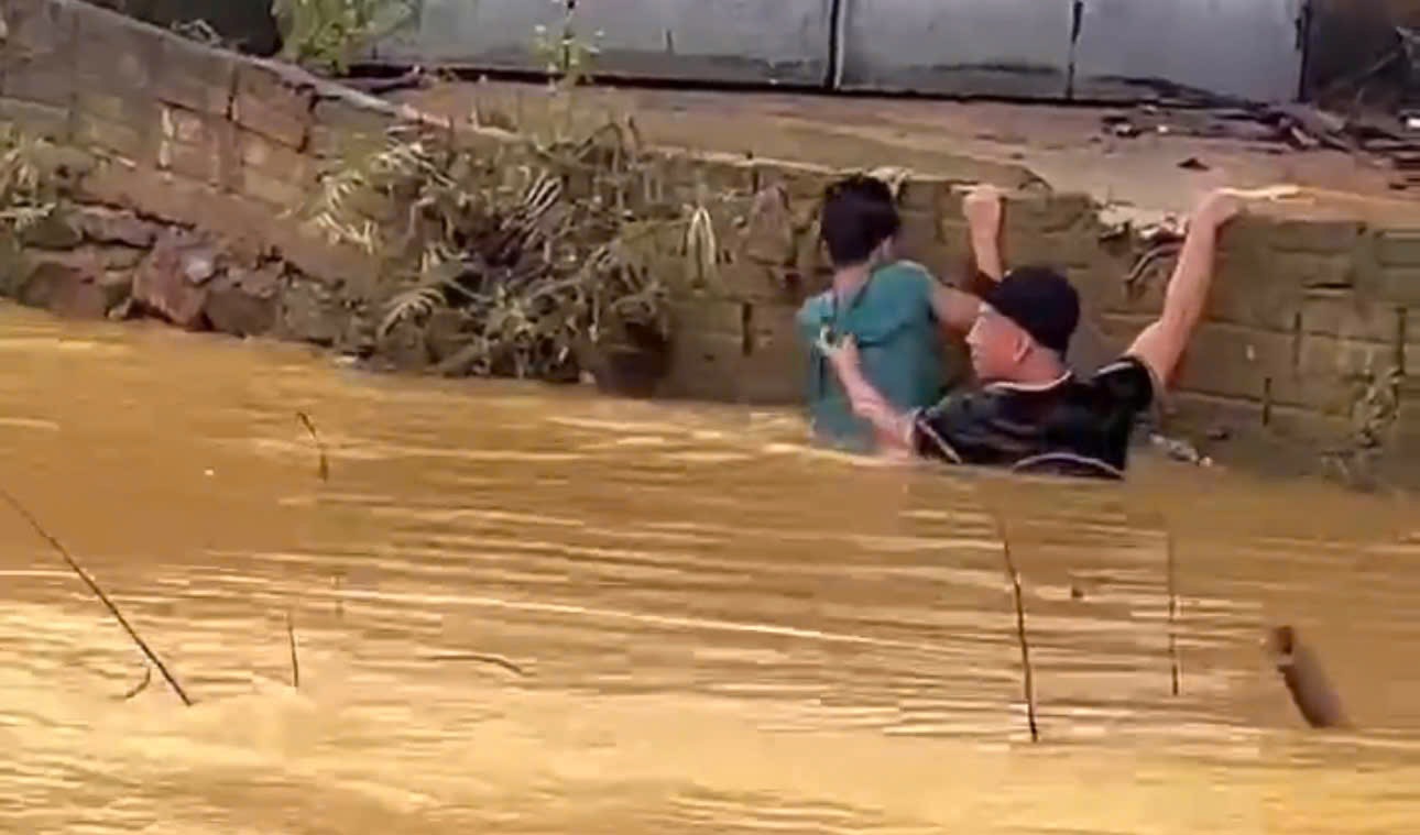 M. Tran The Anh (en noir) au moment ou il nage pour sauver Long emporte par les eaux de crue et ramene a terre. Photo : Tuan Son.