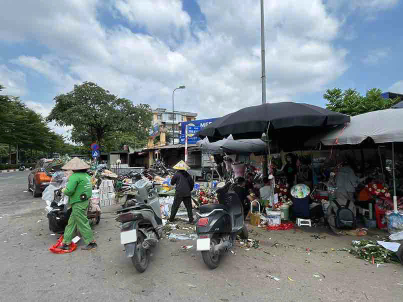 Nhan vien moi truong cung chu cac gian hang hoa quet don de chuan bi thu gom sau ngay buon ban. Anh: Thuy Hien