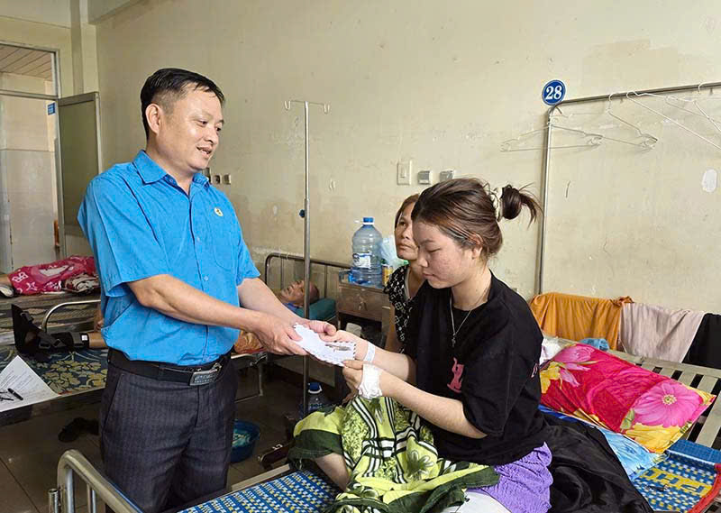 El Sr. Le Thanh Binh - Miembro del Comite Permanente de la Federacion Laboral de la provincia de Quang Ngai - Subjefe del Comite de Trabajo del Sindicato entrega apoyo a la Sra. Dinh Thi Be. Foto: Xuan Quang