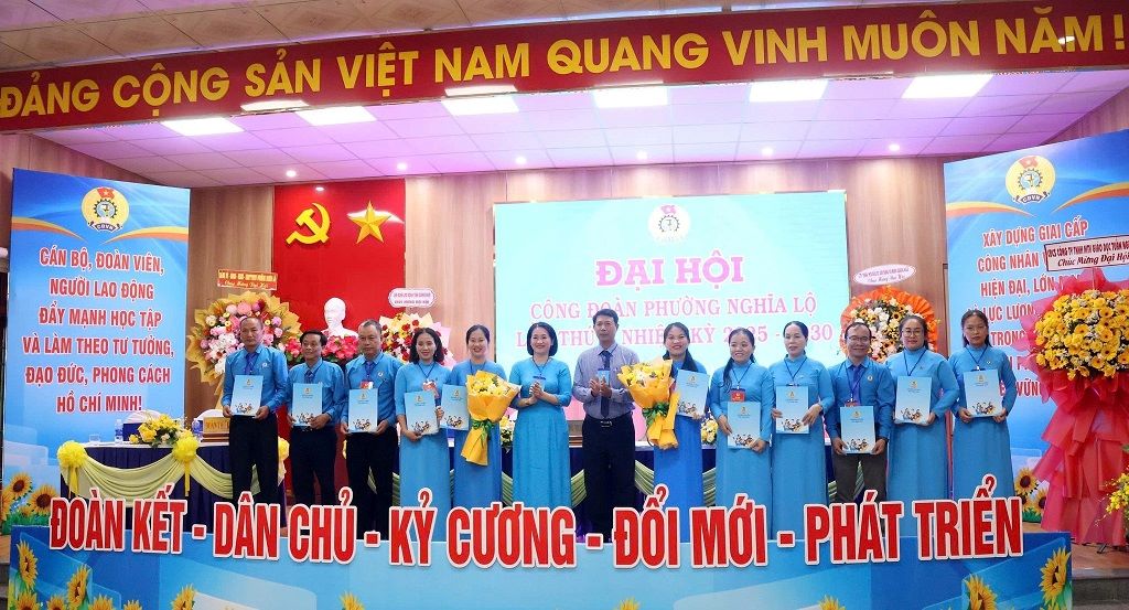 La Sra. Nguyen Thi Anh Lan vicepresidenta del Comite del Frente de la Patria de Vietnam de la provincia presidenta de la Federacion Laboral de la provincia de Quang Ngai (sexto desde la izquierda) entrega la decision y las flores de felicitacion al Comite Ejecutivo del Sindicato de la comuna de Nghia Lo I. Foto: Quoc Chinh