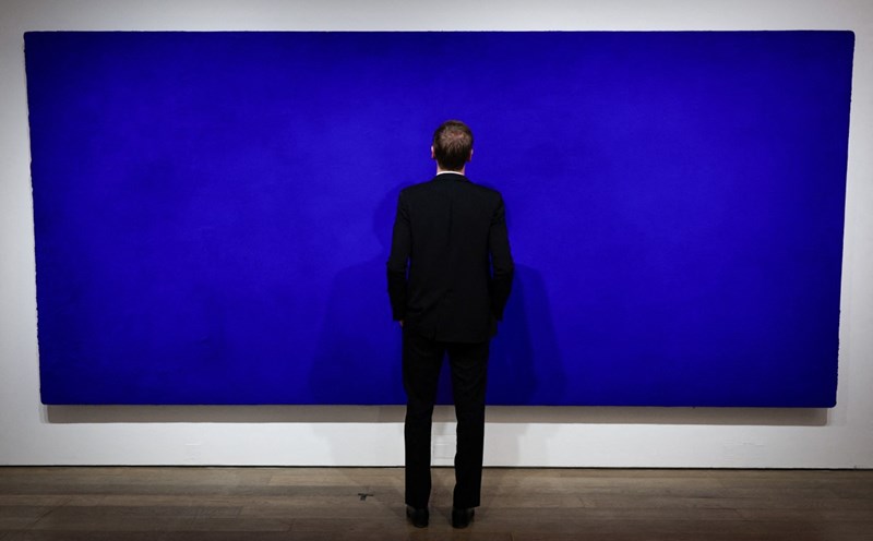 A Christie's employee is viewing a California painting by French artist Yves Klein, displayed at Christie's auction house in Paris. English: AFP