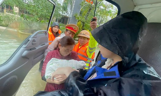 Lực lượng chức năng hỗ trợ thai phụ vùng ngập lụt đến nơi an toàn. Ảnh: Trần Hồng.