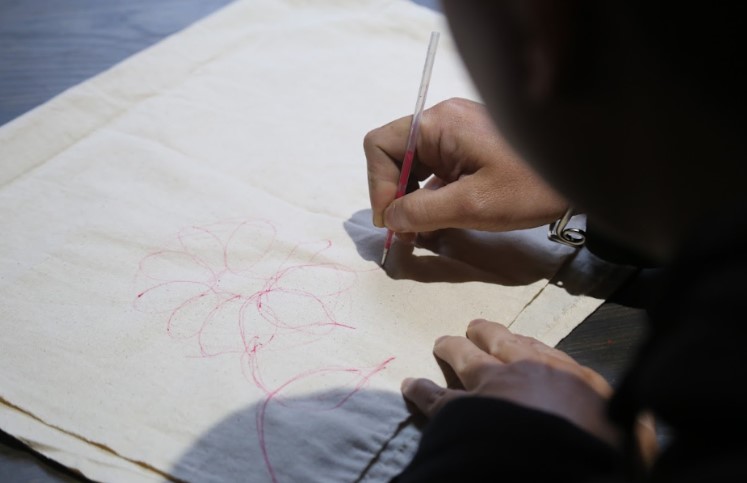 Nguoi tho huong dan du khach ve nhung net ve phac thao dau tien tren vai de lam quen voi bo cuc, san sang truoc khi chuyen sang ve bang sap ong.  