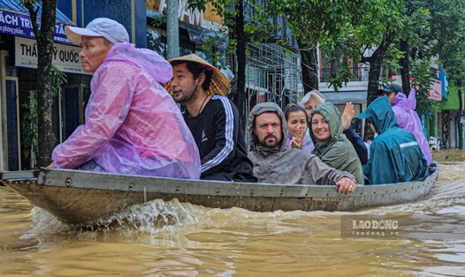 Du khách nước ngoài phải thuê thuyền chở hành lý đi sơ tán khi lũ dâng cao ở Huế. Ảnh: Nguyễn Luân