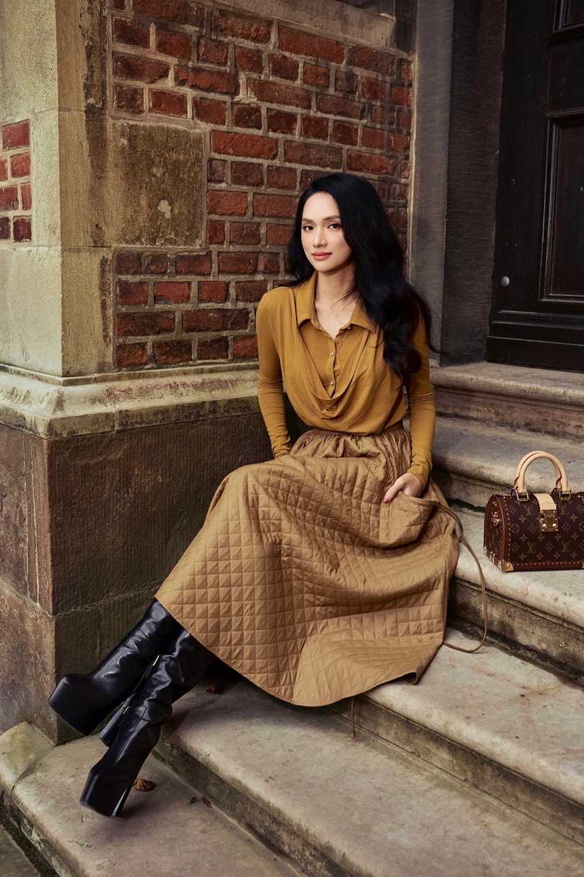 Trong mot thiet ke khac, nguoi dep xuat hien voi ao co draped mem mai phoi chan vay quilted form A, the hien su hoa quyen giua net nu tinh va ky thuat thu cong tinh xao. Gam vang thien olive sang trong ton len lan da va than thai rang ro cua co, giup Huong Giang noi bat giua boi canh tho mong noi troi Au.