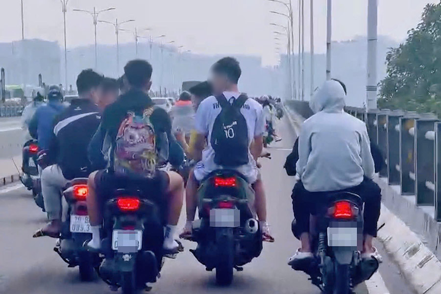 Groupe de jeunes sans casque roulant en rangee sur le pont Vinh Tuy. Photo tiree du clip