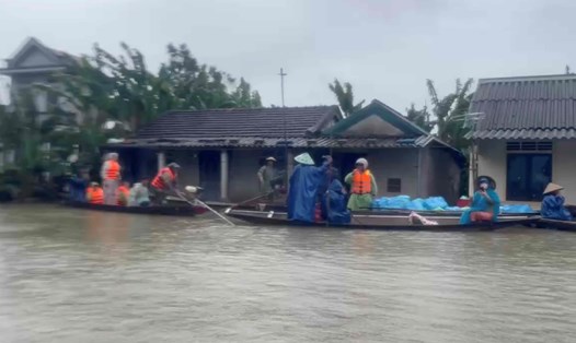 Đi thuyền trên cánh đồng ngập nước tiếp tế cơm nóng cho người dân vùng lũ. Ảnh: H.Nguyên