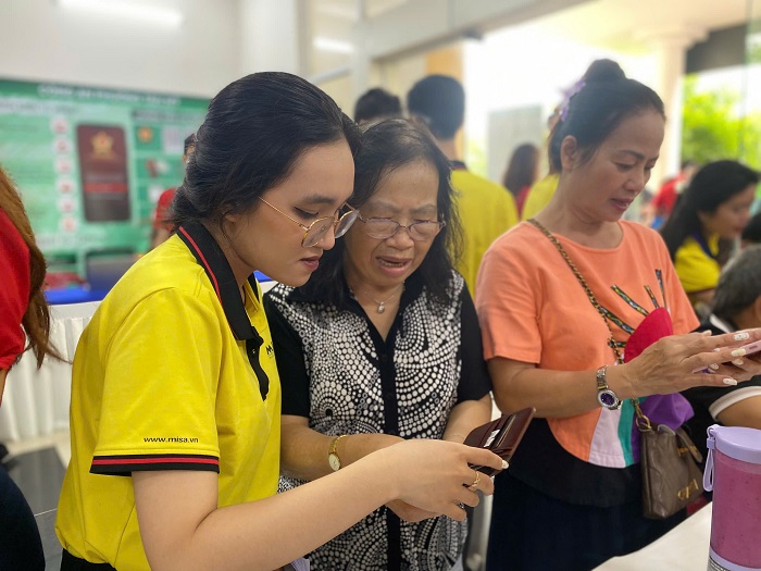 Nhan vien MISA (ao vang) “cam tay chi viec”, huong dan ho kinh doanh lon tuoi su dung phan mem de ban hang, ke khai thue. Anh: MISA