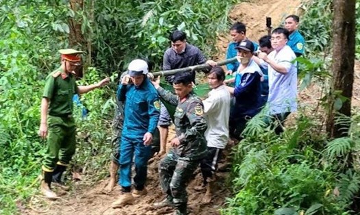 Lực lượng chức năng phối hợp với các y, bác sĩ Trung tâm Y tế Sơn Tây, tỉnh Quảng Ngãi khiêng sản phụ D. theo đường rừng, vượt qua cung đường bị sạt lở. Ảnh: Minh Đan