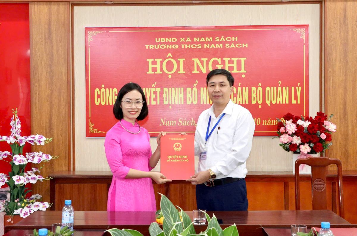 Chu tich UBND xa Nam Sach trao quyet dinh cho ba Ta Thi Hong Anh, Hieu truong Truong THCS Nam Sach. Ảnh: Cong TTDT xa Nam Sach
