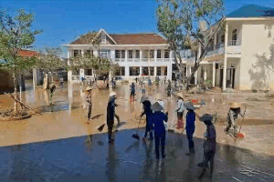 Teachers and parents wade in mud, busy cleaning the school after the flood. Photo: Tran Tuan