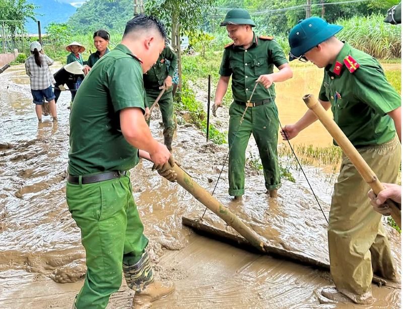 Luc luong Cong an dam mo hoi giup nguoi dan tai xa Dien Lu don dep bun dat sau bao so 10. Anh: Cong an Thanh Hoa