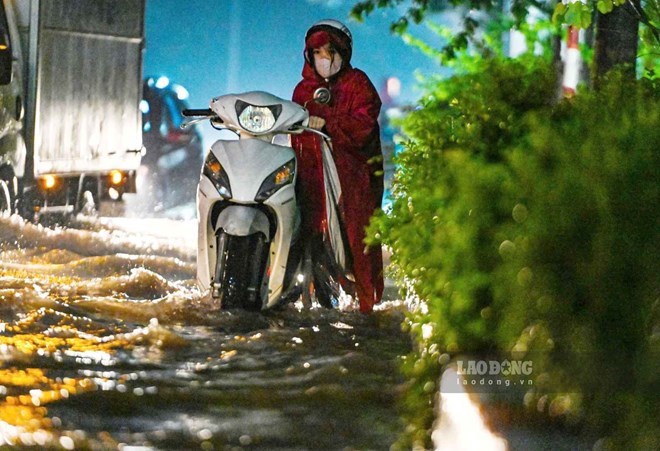 Hanoi residents struggle to get their vehicles home after heavy rain due to the impact of the storm. Photo: To The