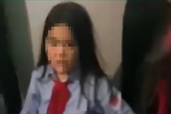 Estudiante rodeada por amigos que la golpean y la obligan a arrodillarse con rodillas y brazos. Foto: Captura del clip