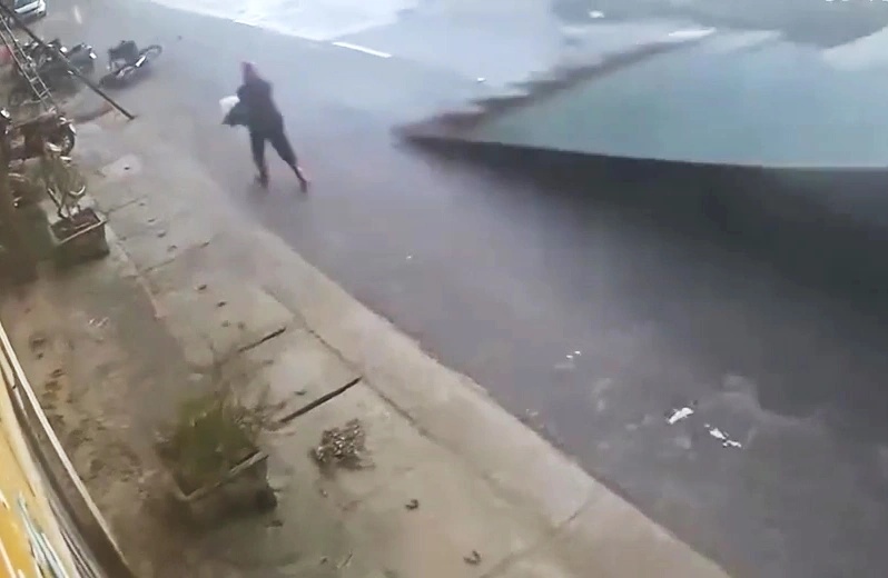 The woman quickly ran away before the corrugated iron roof was swept away by the thunderstorms and plunged onto the road. Photo: Cut from clip
