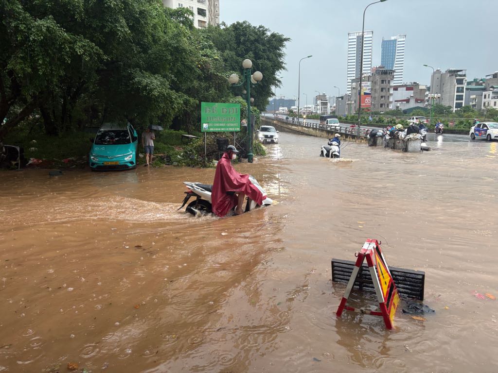 Một người dân đi xe máy qua đoạn ngập sâu. Ảnh: Bảo Hân 