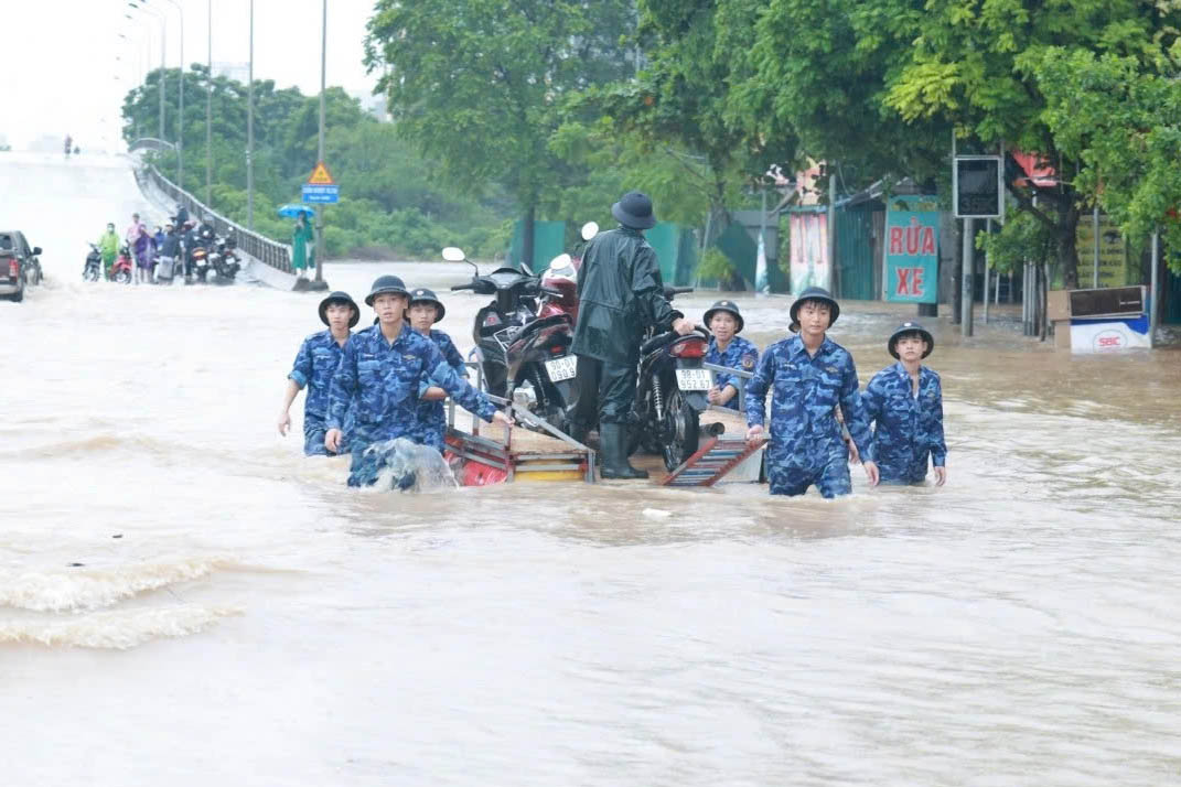 Officers and soldiers of the Vietnam Coast Guard assisted people through the deep flooded point at Nga bridge (Xuan Phuong ward, Hanoi) on October 7. Photo: Ha Phuong