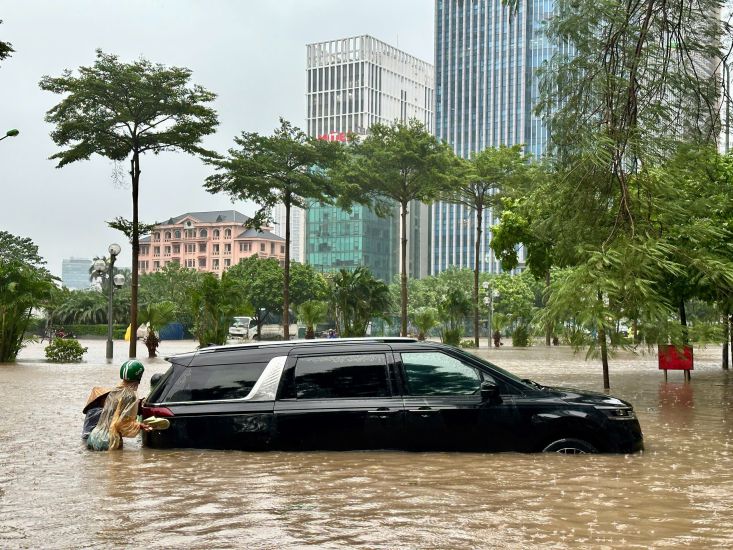 People assisted the driver in pushing the car out of the flooded area. Photo: Tuan Anh