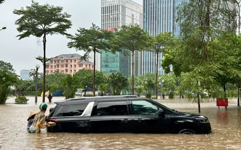 People assisted the driver in pushing the car out of the flooded area. Photo: Tuan Anh