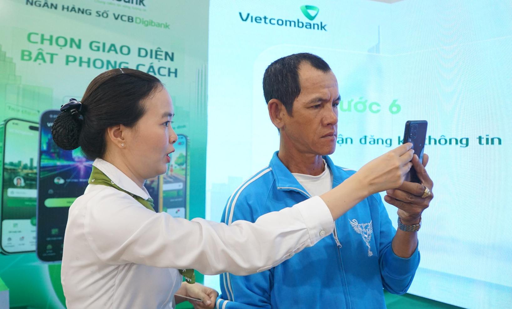 Nhan vien ngan hang huong dan khach hang thuc hien giao dich khong giay. Anh: Nhat Ho