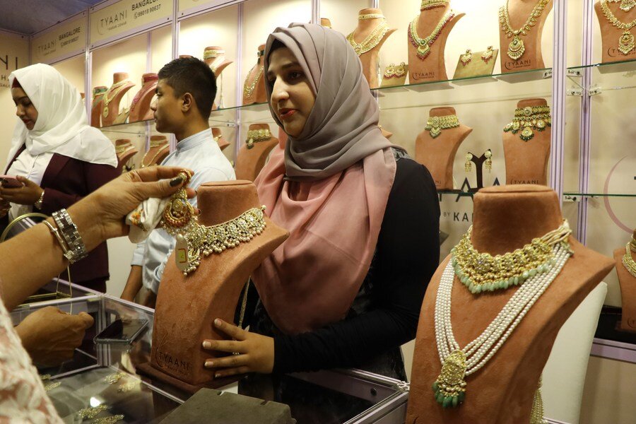 Indian women try gold jewelry at the 2023 Asian Jewelry Exhibition in Bengaluru, India. Photo: Xinhua