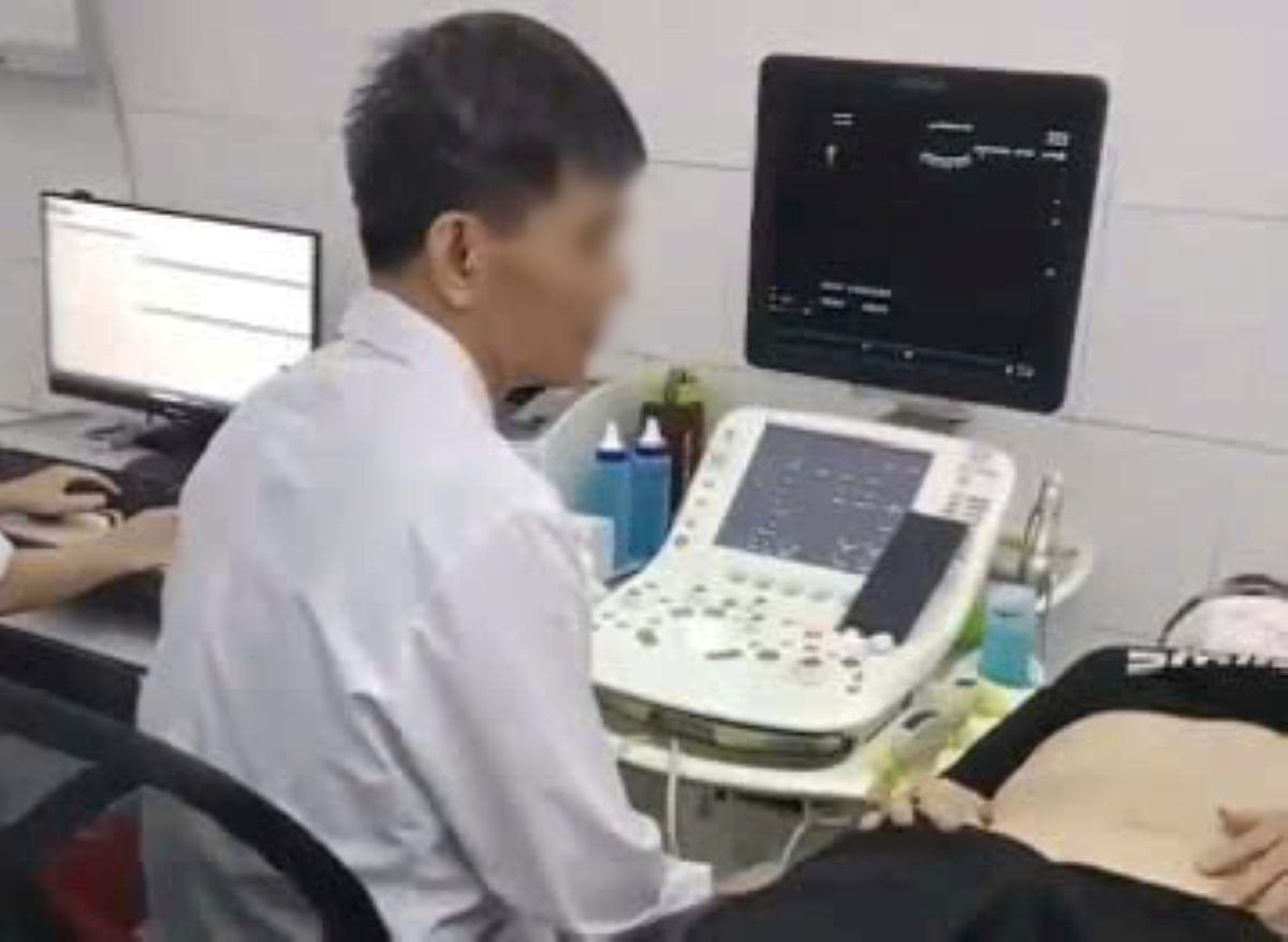 Bac si bi “to” vua xem dien thoai vua sieu am. Anh: Cat tu clip nguoi nha benh nhan.