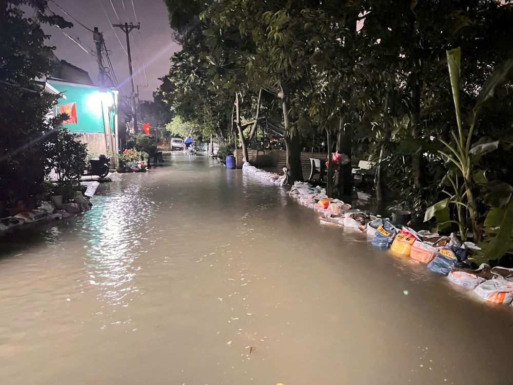 Nuoc dang nhanh tran qua mat duong, nguoi dan huy dong bao cat dap tam bo bao. Anh: Anh Tu