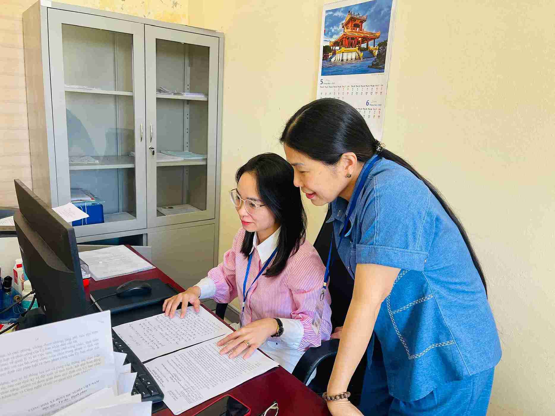 La Sra. Nguyen Thi Tham esta directamente de pie junto a cada funcionario explicando pacientemente cada operacion en el ordenador. Foto: Mai Huong