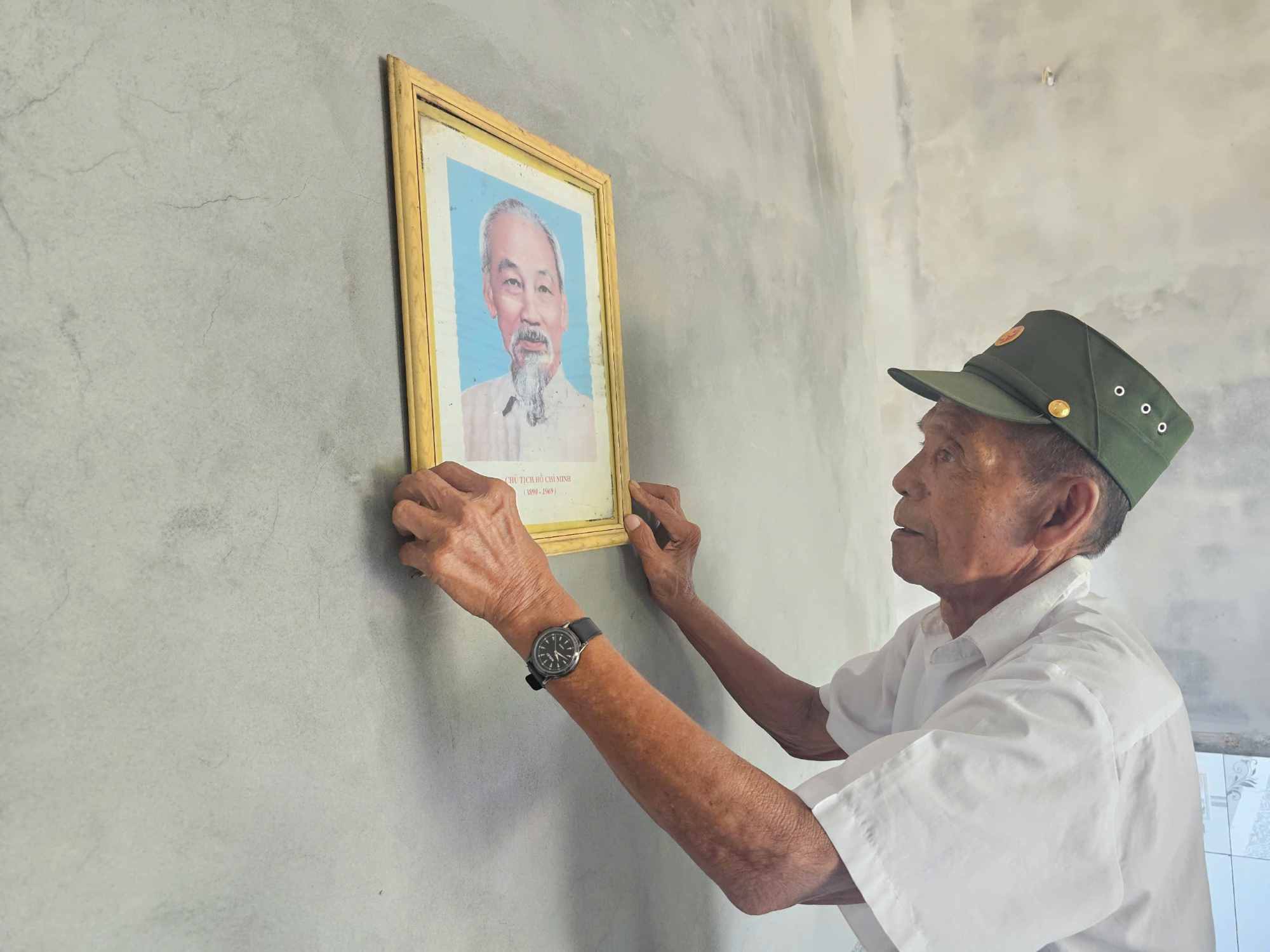 Ong Ho Van Hong can than treo anh Bac Ho vao vi tri trang trong nhat cua can nha moi. Anh: Han Nguyen