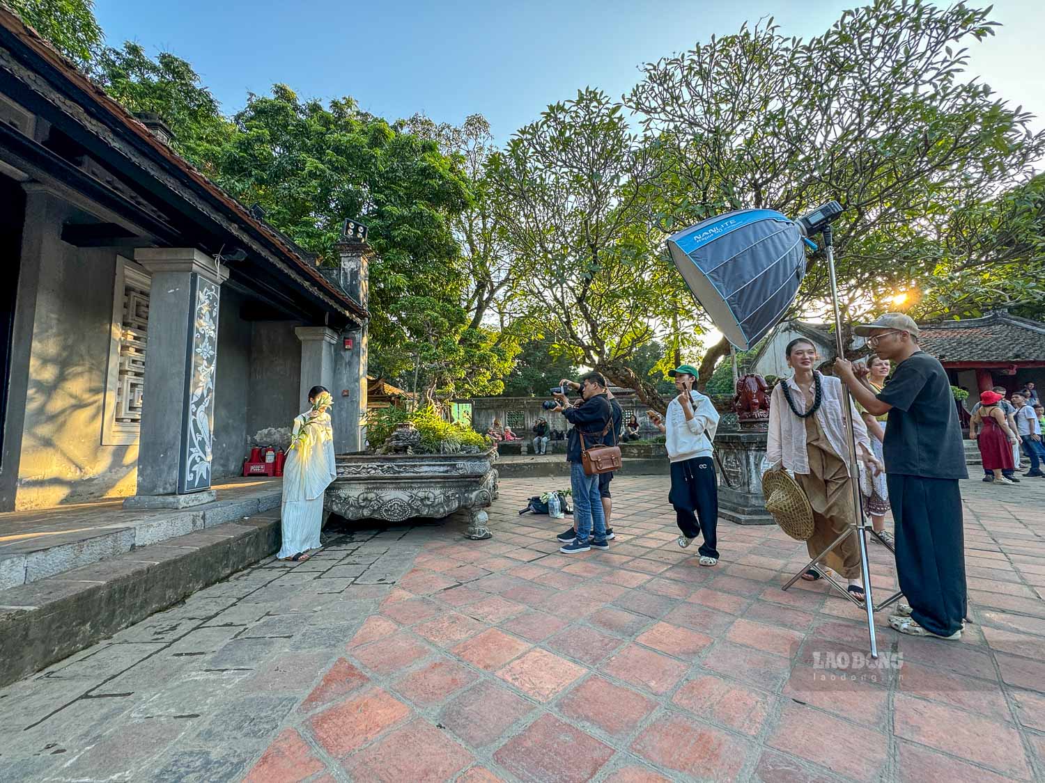 Khong khi nhon nhip tai san Van Mieu trong mot ngay nang dep; nhieu nhom chup anh hoat dong song song, tao nen khung canh soi dong nhu mot “phim truong” ngoai troi.