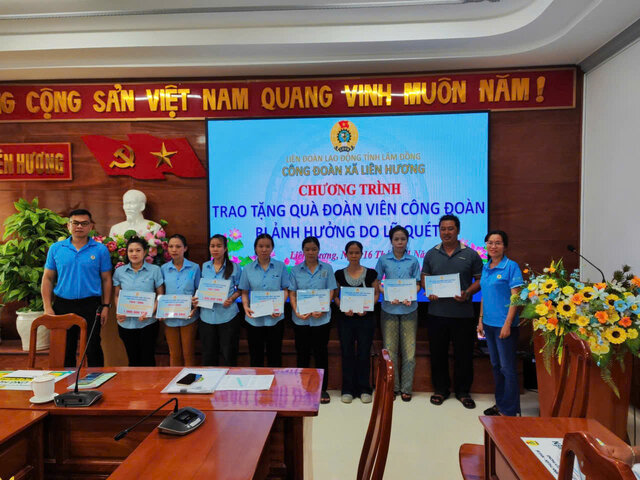 Anh Nguyen Hoa – Chu tich Cong doan co so Xi nghiep May Tuy Phong (ben trai) trao ho tro nguoi lao dong bi thiet hai do lu lut. Anh: Duc Lam