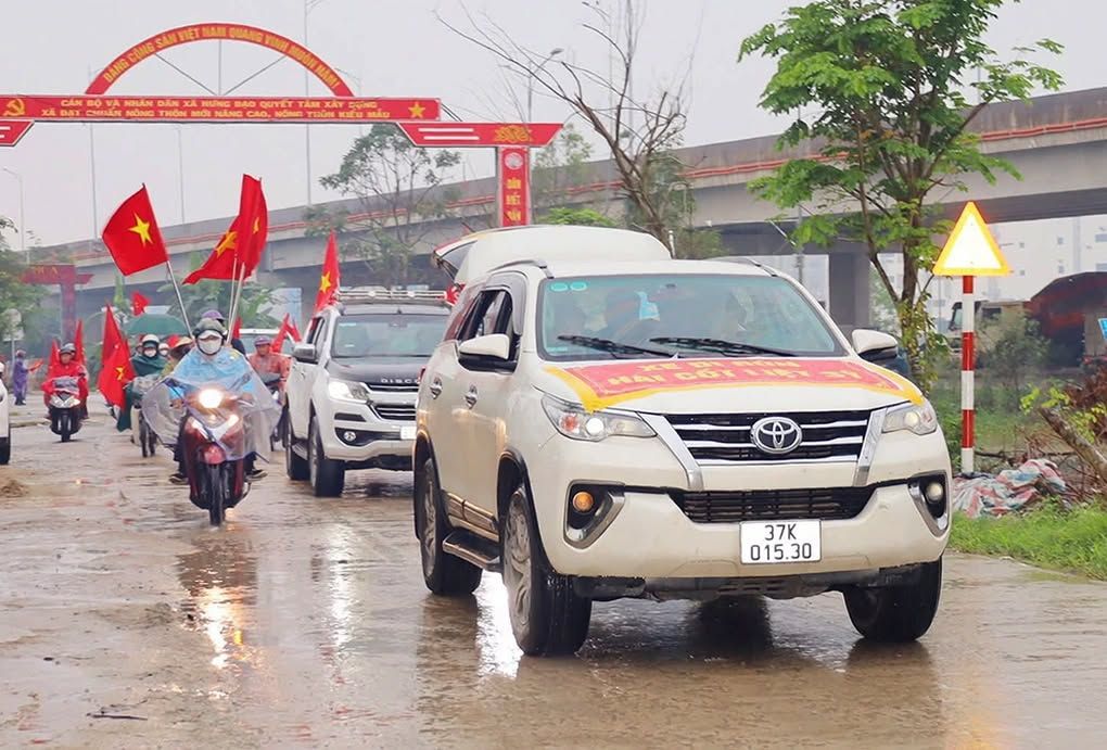 People brave the rain to welcome the remains of martyr Nguyen Van Son back to his hometown. Photo: KI'U HOA
