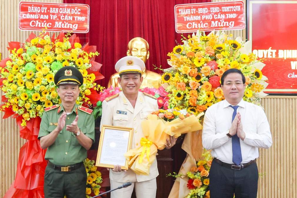 Ong Tran Van Huyen va Thieu tuong Huynh Viet Hoa trao Quyet dinh va hoa chuc mung Thuong ta Ly Hoang Phong. Anh: Cong an Can Tho