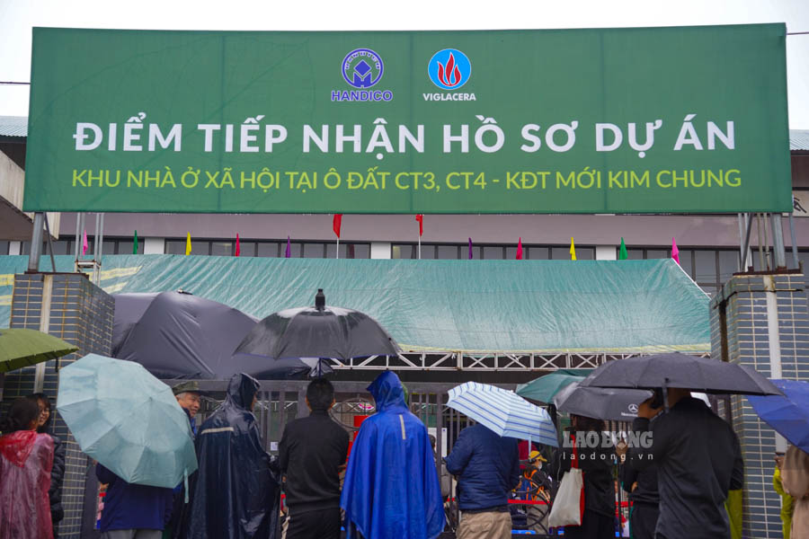 Cargando casi 1 km bajo la lluvia esperando presentar los expedientes para comprar viviendas sociales en Hanoi. Foto: Tuan Anh