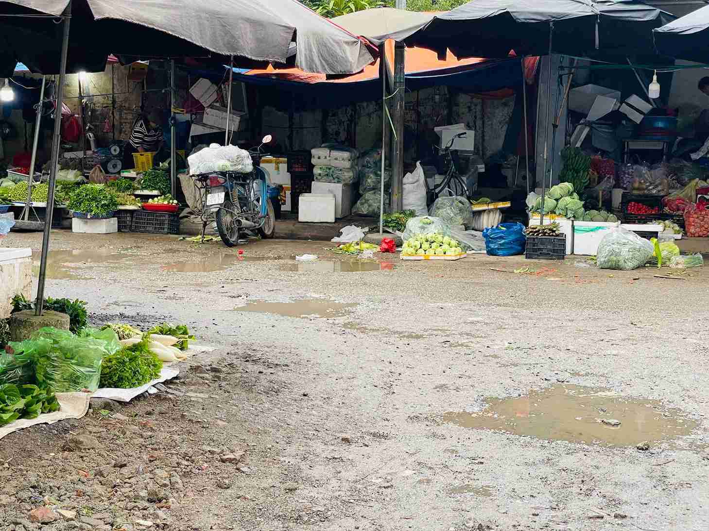 Vũng nước đọng sau mưa trên tuyến đường chính trong chợ, tiềm ẩn nguy cơ trượt ngã.
