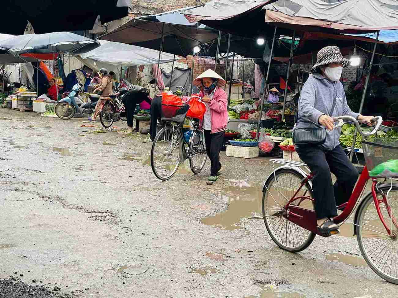 Người dân băng qua đoạn đường lầy lội, ổ gà khiến việc di chuyển chậm và khó khăn.
