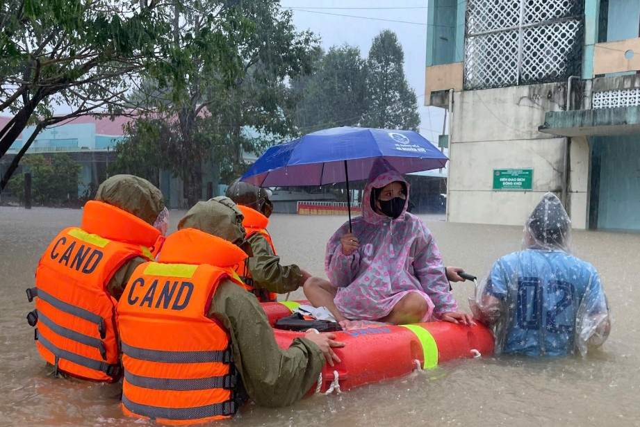 The mother Trinh Thi Kim Lan (residing in My Phu village, Hoa Thinh commune, Dak Lak) was supported by the police to overcome the flood to get to the commune health station safely. Photo: Provided by the police