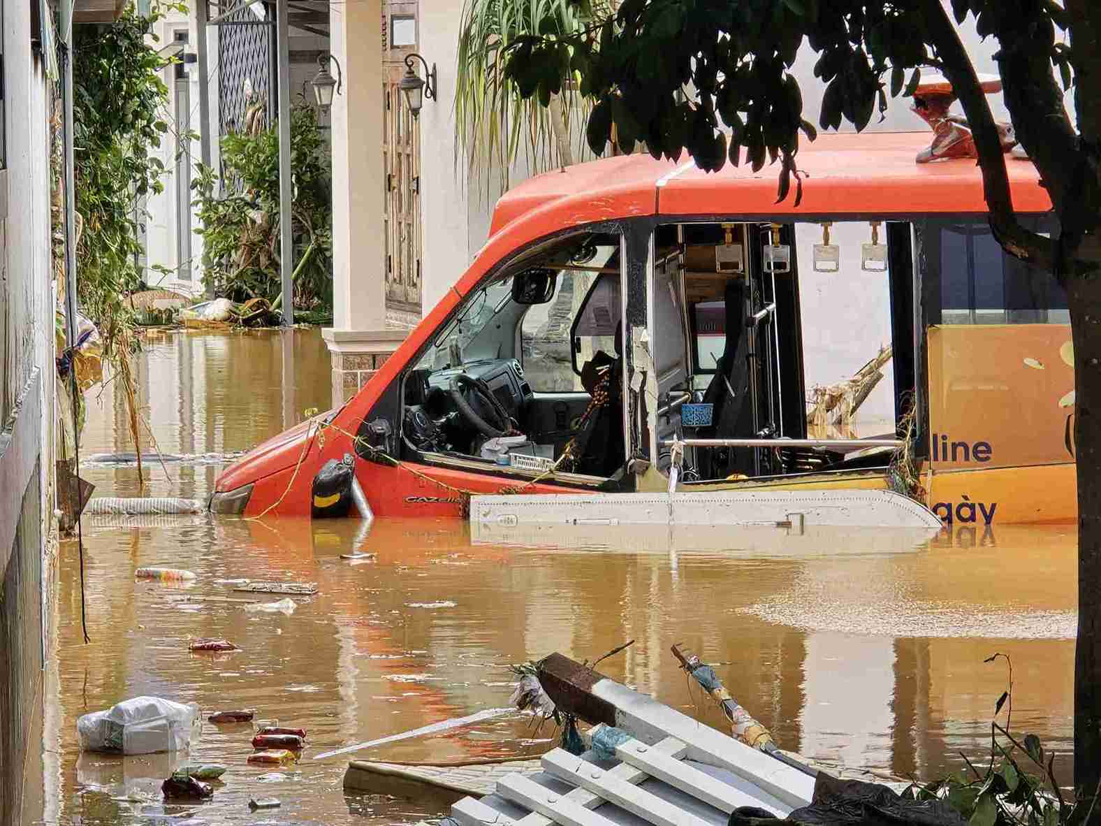 Xe buyt cua mot doanh nghiep tren dia ban xa D'ran bi nuoc lu dang cao nhan chim. Anh: Phuc Khanh