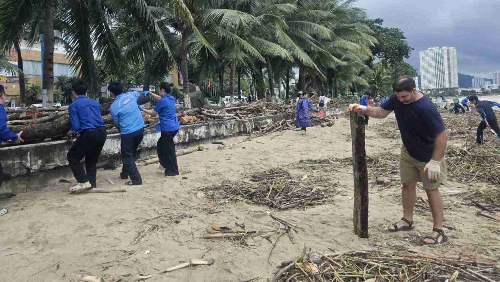 Les touristes unissent leurs forces pour nettoyer les dechets sur la plage de Nha Trang apres le retrait des inondations. Photo : Binh Quy