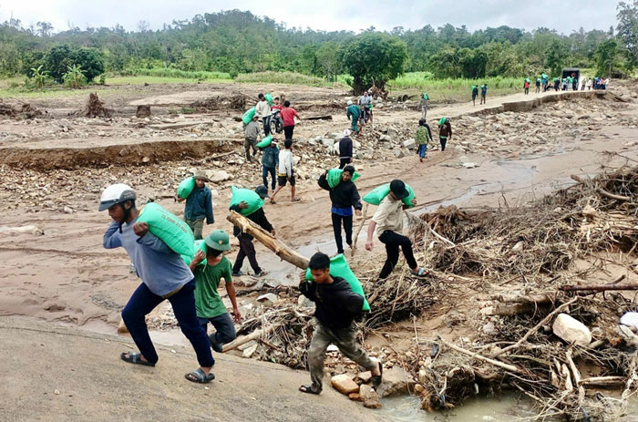 Hrach村の住民が洪水による道路の損傷を乗り越えて、救援物資や必需品を受け取る。写真:Ngoc Son