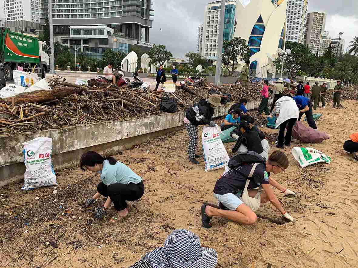 Des membres de la delegation et des travailleurs lancent un defile pour nettoyer la plage de Nha Trang apres les inondations. Photo : Huu Thong