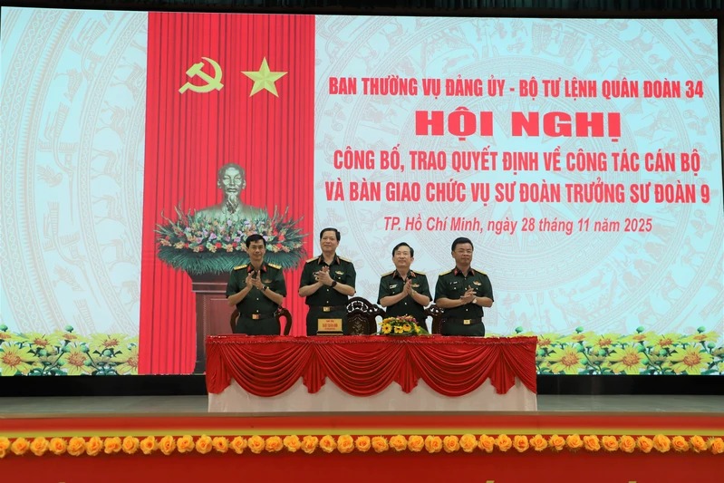 Trung tuong Dao Tuan Anh - Pho Bi thu Dang uy, Tu lenh Quan doan 34 va Thieu tuong Le Minh Quang - Bi thu Dang uy, Chinh uy Quan doan 34 chung kien Dai ta Ngo Ngoc An (bia trai) va Dai ta Le Van Quyet ky bien ban ban giao nhiem vu. Anh: Nguyet Phuong