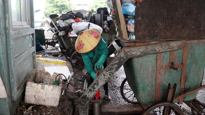 Nu cong nhan tat bat thu gom, van chuyen rac duoi chan cau vuot duong Nguyen Xien. Anh: My Linh