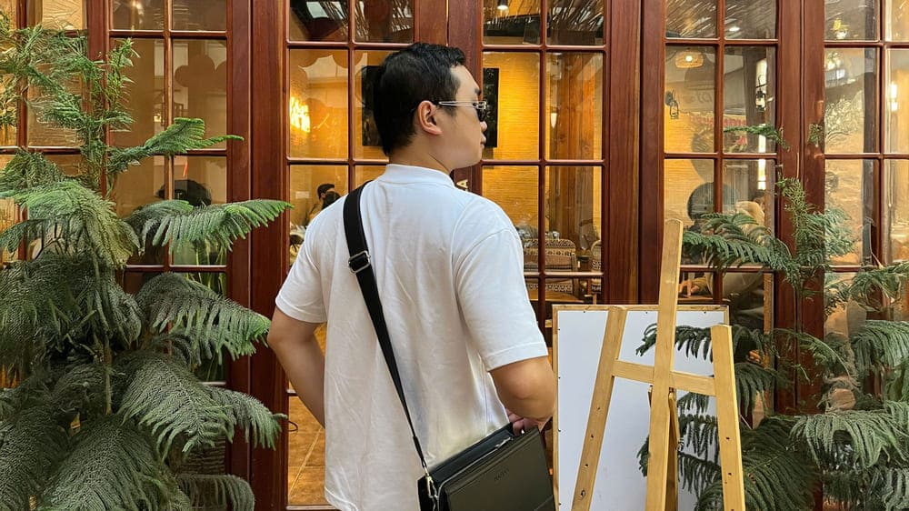 クロスオーバーの革製バッグは、男性が白いシャツと簡単に組み合わせるのに役立つアクセサリーです。写真:トゥアン・ダット