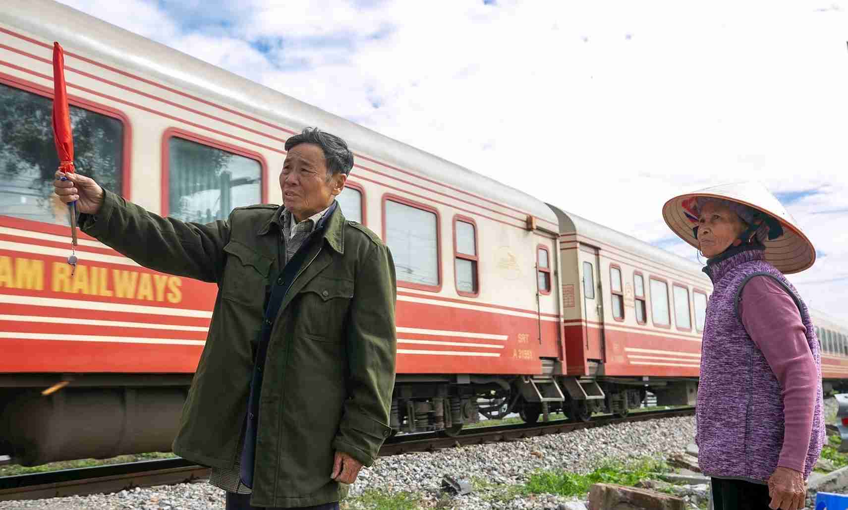 Dang夫妻が各列車を注意深く見守り、住民の安全な通行を確保する瞬間。写真:Hai Minh