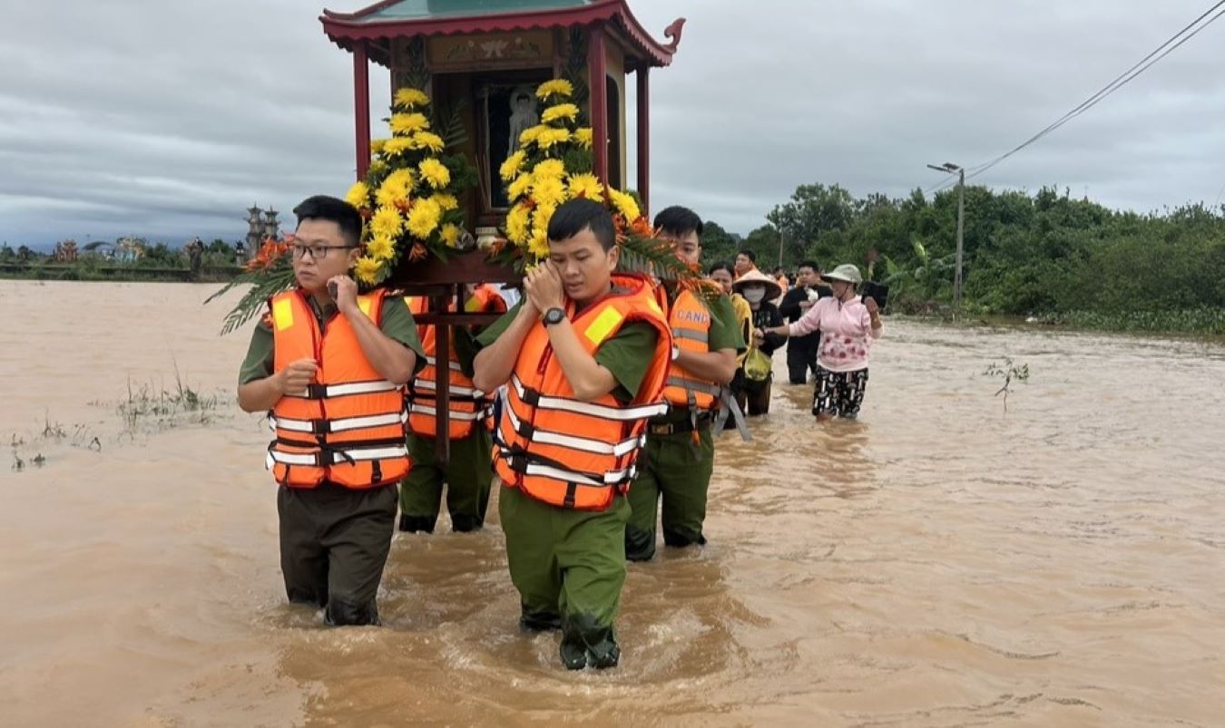 공안 병력이 홍수로 침수된 도로 구간을 통해 장례 행렬을 돕고 있습니다. 사진: T.Vu