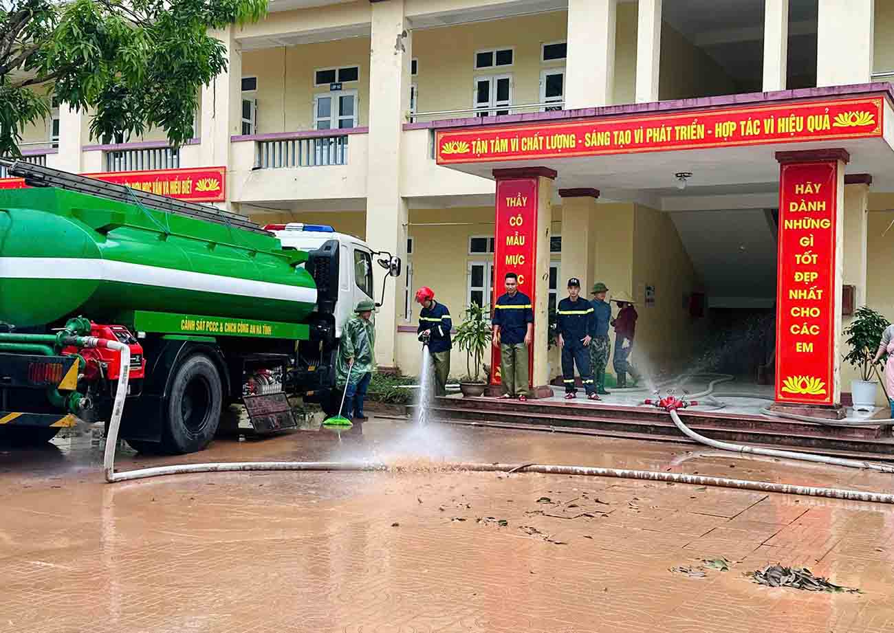 Ha Tinh Police used a water tank truck to help My Due Secondary School clean up mud after the flood. Photo: Cam My