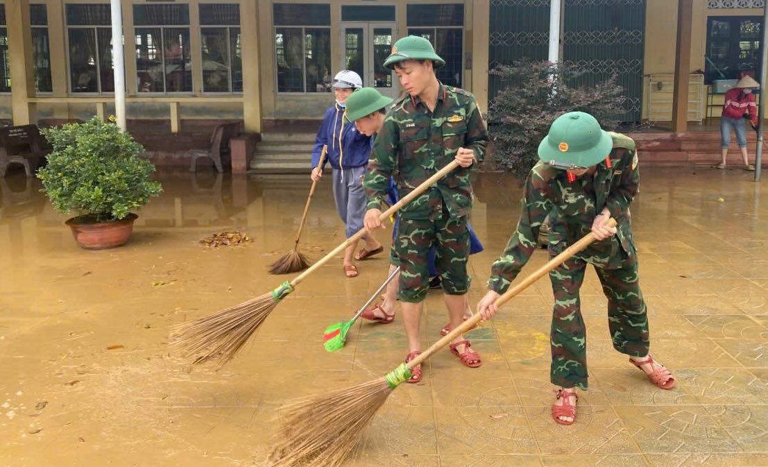 Armed men and people clean up after the flood. Photo: Quang Tri Provincial Military Command